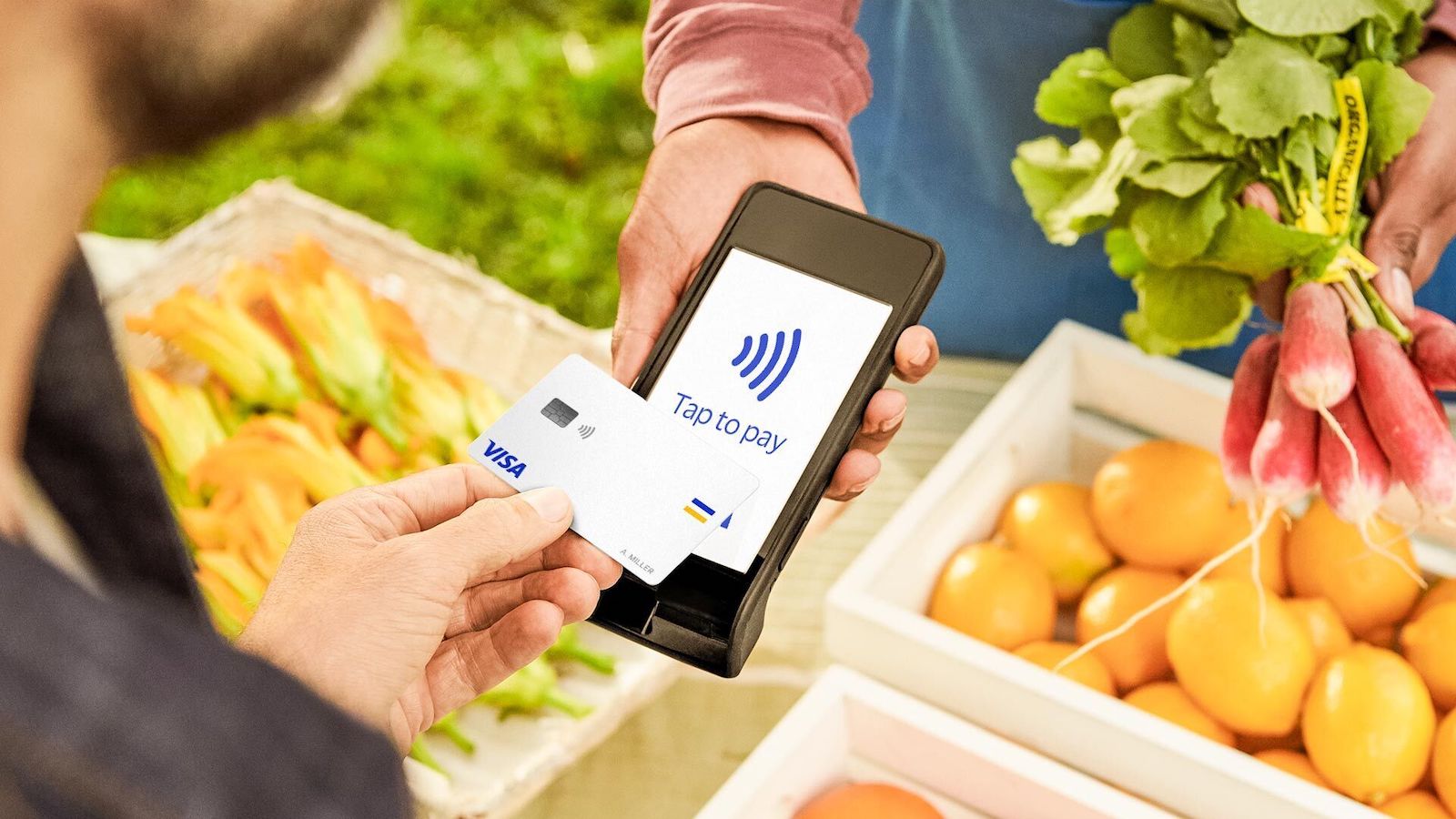 person paying for fruit and vegetables at a grocery stall